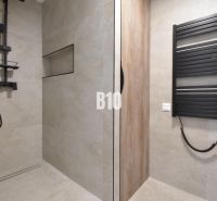 Badezimmer in einer 4-Zimmer-Wohnung mit moderner Dusche und schwarzem Heizkörper.