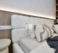 Schlafzimmer mit einem Kopfteil und Regalen in einer 4-Zimmer-Wohnung, mit sanfter Beleuchtung.