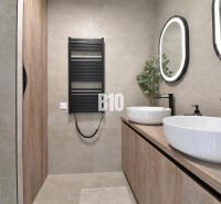 Ein Badezimmer in einer 4-Zimmer-Wohnung mit ovalen Spiegeln und Möbeln mit Holzdekor.