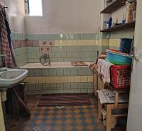Badezimmer im Einfamilienhaus mit Mosaikfliesen und Badewanne, auf Holzdekor.