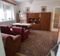 Wohnzimmer in einem Einfamilienhaus mit einer Sitzgarnitur, einem Schrank und einem Kronleuchter, Boden mit Holzdekor.