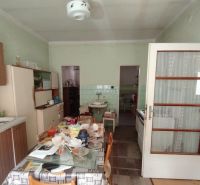 Eine Küche in einem Einfamilienhaus mit einfacher Einrichtung und einem Esstisch, Boden mit Holzdekor.