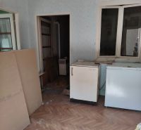 Ein Zimmer in einem Einfamilienhaus mit einem Holzboden und älteren Möbeln.