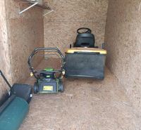 Ein Holzunterstand mit Gartentechnik, einschließlich Rasenmähern, in den Gärten.
