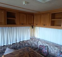 Interieur eines Wohnmobils mit Sofa, Schränken und Vorhängen, Gärten, dekorativer Tisch.