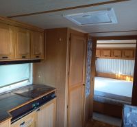 Das Innere eines Wohnmobils mit Küche und Schlafzimmer, Holzboden, Gärten.
