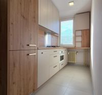 Küche in einer Einzimmerwohnung mit Holzdekor und eingebauten Geräten.