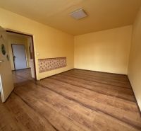 Ein Zimmer mit einem Holzboden in einer Einzimmerwohnung mit gelben Wänden.