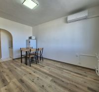 Einzimmerwohnung mit Holzboden, Esstisch, Klimaanlage, einfache Einrichtung.