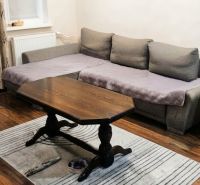 Wohnzimmer einer 3-Zimmer-Wohnung mit Sofa, Tisch, Holzboden und Teppich.
