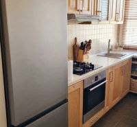Küchenzeile in einer 3-Zimmer-Wohnung mit Holzschränken und Geräten.