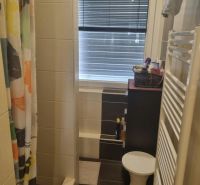 Badezimmer mit gefliester Dusche, Vorhang und Fenster in einer 3-Zimmer-Wohnung.