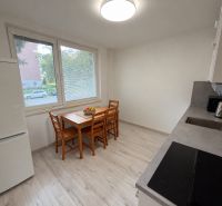 Küche in einer 2-Zimmer-Wohnung mit Holzboden, Esstisch und Geräten.