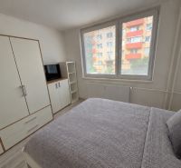 Helles Schlafzimmer in einer 2-Zimmer-Wohnung mit großem Bett, weißem Kleiderschrank und Fernseher.