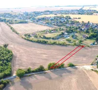 Landwirtschaftliche und forstwirtschaftliche Flächen in Podhájska, umliegende Felder und entfernte Gebäude.