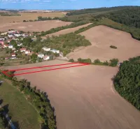 Luftaufnahme von landwirtschaftlichen und forstwirtschaftlichen Flächen bei Podhájska, umgeben von Dorf und Wald.