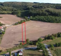 Ländliche Aussicht auf landwirtschaftliche und forstwirtschaftliche Flächen in Podhájska, die eine Siedlung mit Einfamilienhäusern umgeben.