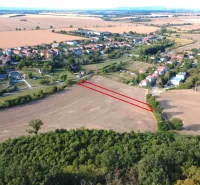 Luftaufnahme von landwirtschaftlichen und forstwirtschaftlichen Flächen in Podhájska, mit dem Dorf im Hintergrund.