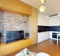 Wohnzimmer in einer 2-Zimmer-Wohnung mit Ziegelwand, Möbeln und Boden in Holzoptik.