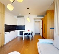 Die Küche einer 2-Zimmer-Wohnung mit weißen Möbeln, einem Boden in Holzoptik und einem Esstisch.