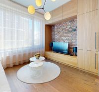Wohnzimmer in einer 2-Zimmer-Wohnung mit Ziegelverkleidung, Fenster und Boden in Holzoptik.