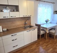 Küche im Einfamilienhaus mit weißen Schränken und einem Boden in Holzoptik.