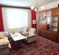 Wohnzimmer in einem Einfamilienhaus mit bequemen Sofas, einem Holzschrank und einem roten Teppich.