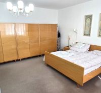 Schlafzimmer in einem Einfamilienhaus mit Holzmöbeln, Teppichboden und Wanddekorationen.