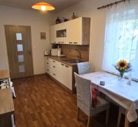 Küche in einem Einfamilienhaus mit Holzboden und Blumen auf dem Tisch.