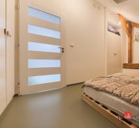 Schlafzimmer mit Holzelementen, einem Bett aus Paletten und Stauraum in einer 3-Zimmer-Wohnung.