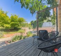 Terrasse in einer 3-Zimmer-Wohnung mit Holzelementen, Garten und Außenbereich zum Sitzen.