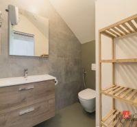 Badezimmer in einer 3-Zimmer-Wohnung mit Waschbecken, Holzregal und Spiegel an der Wand.