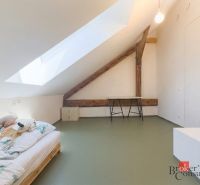 Dachzimmer mit Bett, Holzboden und Dachfenster in einer 3-Zimmer-Wohnung.