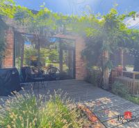 Terrasse mit Grün, Holzelementen und Sitzgelegenheiten im Garten einer 3-Zimmer-Wohnung.