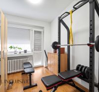 Fitnessstudio im Einfamilienhaus mit Bank, Hanteln und Boden in Holzoptik.