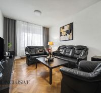 Wohnzimmer in einem Einfamilienhaus mit schwarzen Ledermöbeln und einem Fernseher.
