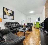 Wohnzimmer in einem Einfamilienhaus mit schwarzen Ledermöbeln und einem Boden in Holzoptik.
