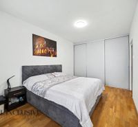 Schlafzimmer mit großem Bett, Nachttisch und Boden mit Holzdekor in einem Einfamilienhaus.