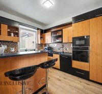 Eine Küche mit schwarzen Möbeln und einem Holzboden in einem Einfamilienhaus.