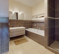 Badezimmer in einer 4-Zimmer-Wohnung mit Badewanne, Dusche und Stauraum.