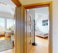 Innenraum einer 4-Zimmer-Wohnung mit Holzboden, Sessel und hellen Räumen.