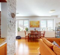 Wohnzimmer mit Sofa, Esstisch und Boden in Holzoptik.