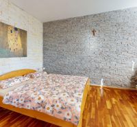 Schlafzimmer mit Steinwänden, Bett und Sessel, Boden mit Holzdekor.