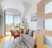 Ein Zimmer mit einem Sofa und einem Sessel, großes Fenster, Boden mit Holzdekor, 4-Zimmer-Wohnung.