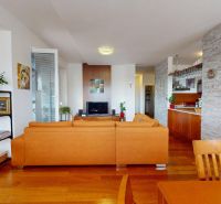 Wohnzimmer mit hellen Elementen, Ledersofa und Boden in Holzoptik.