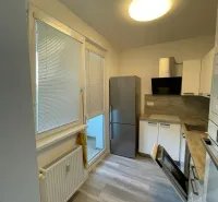 Küche in einer 2-Zimmer-Wohnung mit Holzboden, weißen Schränken und eingebautem Gerät.