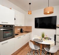 Kompakte Küche in einer Einzimmerwohnung mit Holzboden und Essecke.