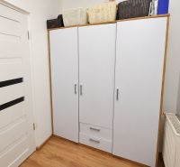 Weißer Schrank mit Körben, Türen und Boden mit Holzdekor in einer Einzimmerwohnung.