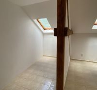 Podkrovný priestor kancelárie s dreveným trámom a strešnými oknami.  
-  
Dachbodenbüro mit Holzbalken und Dachfenstern.