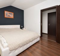 Helles Schlafzimmer mit Bett und Holzboden in einem Einfamilienhaus.